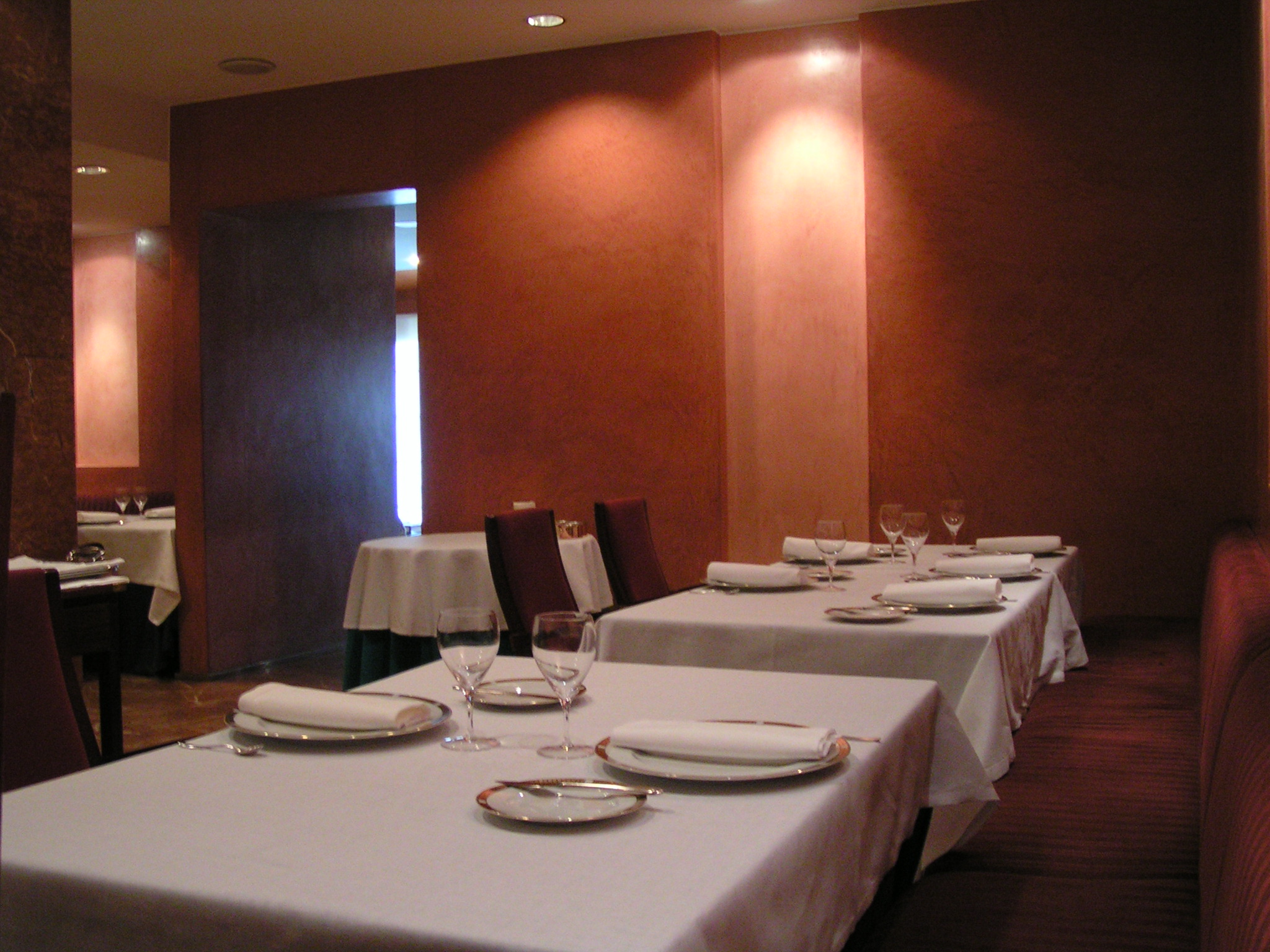 Restaurant dining room with white tablecloths, wine glasses and folded napkins
