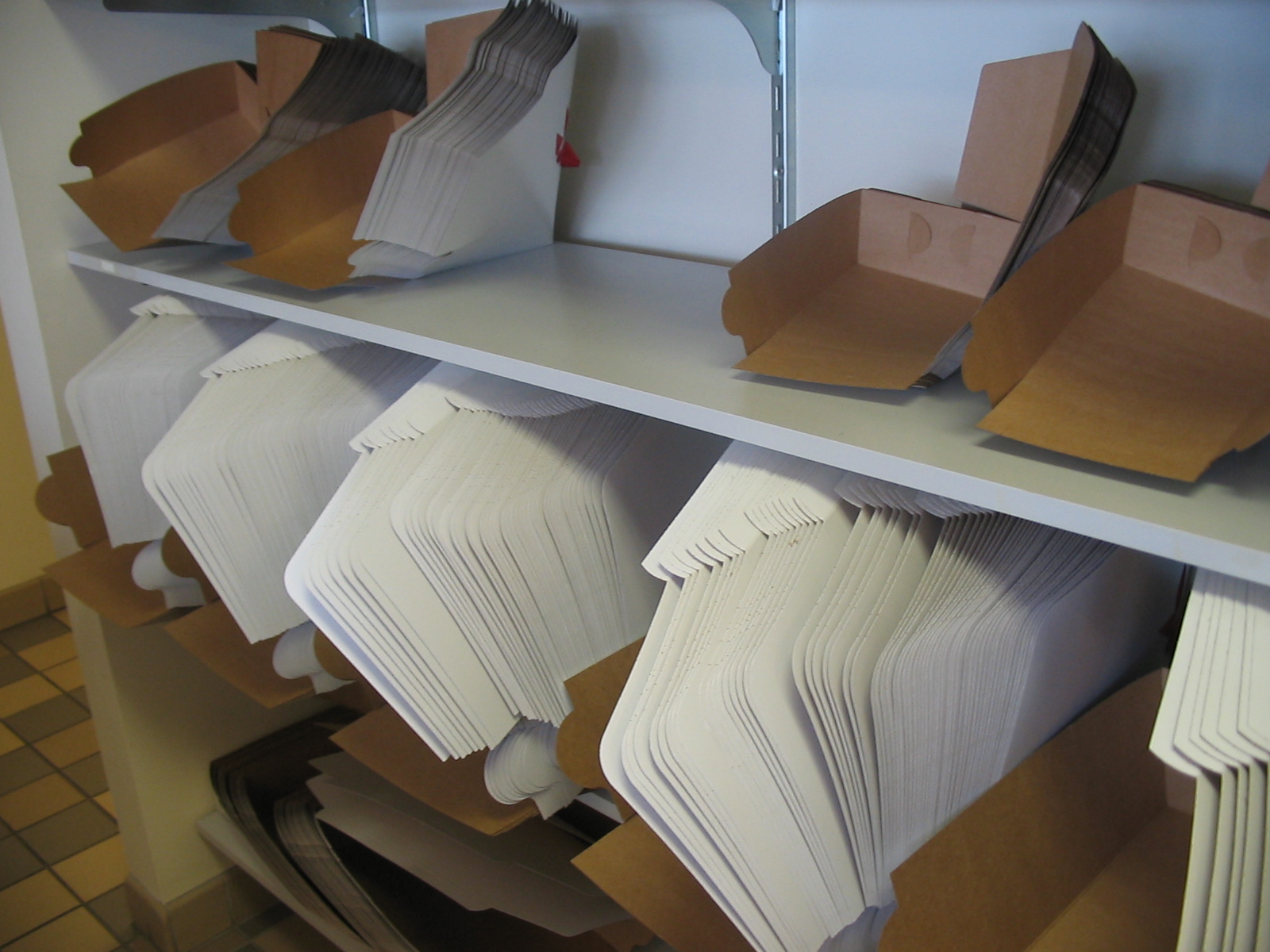 Stacks of part-folded cake boxes on shelves, ready to be assembled for orders