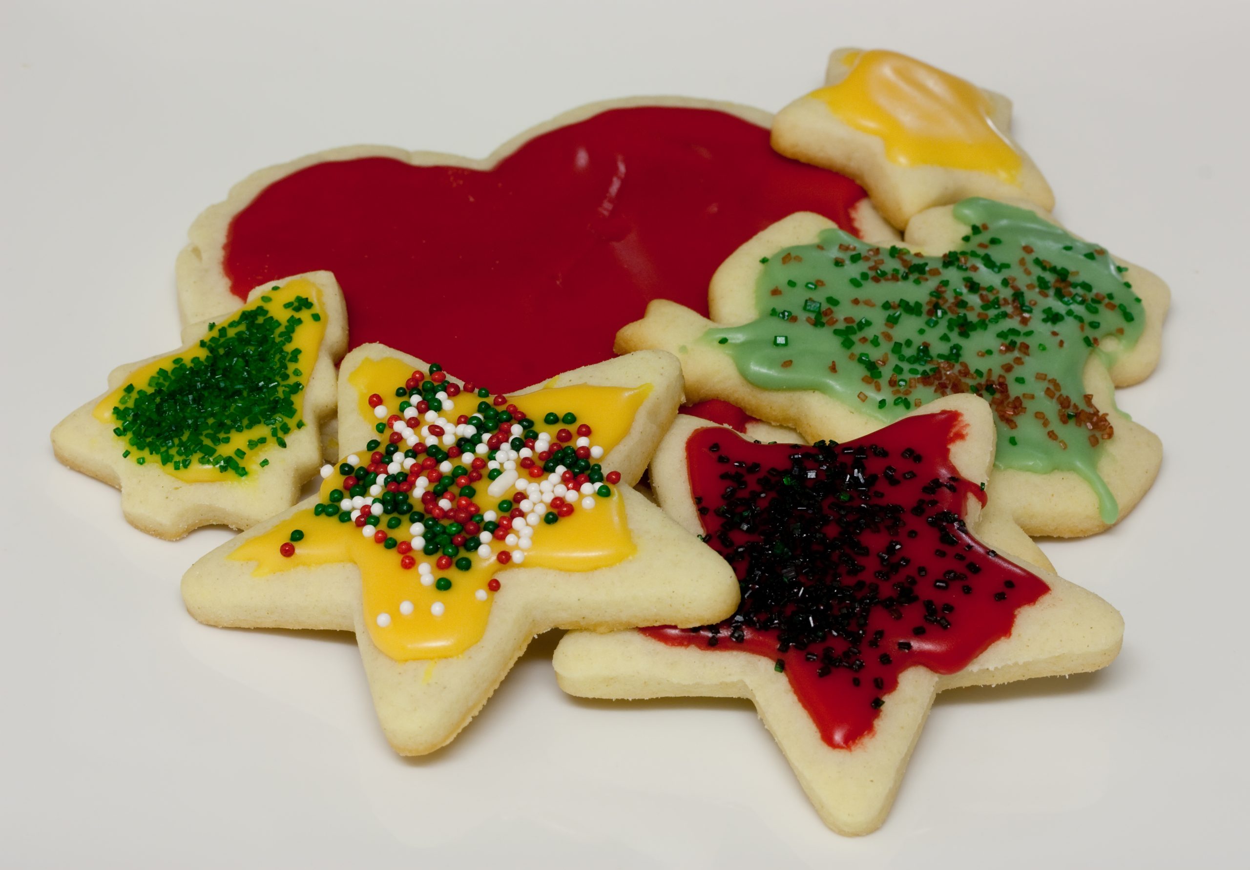Star, heart and tree shaped sugar cookies with colored icing and sprinkles on a white background